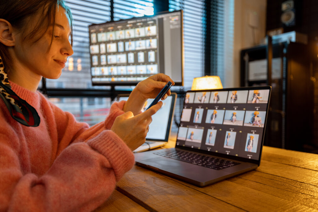 Young creative woman work on phone and computers editing photos at cozy home office. Portrait of female photographer at home studio